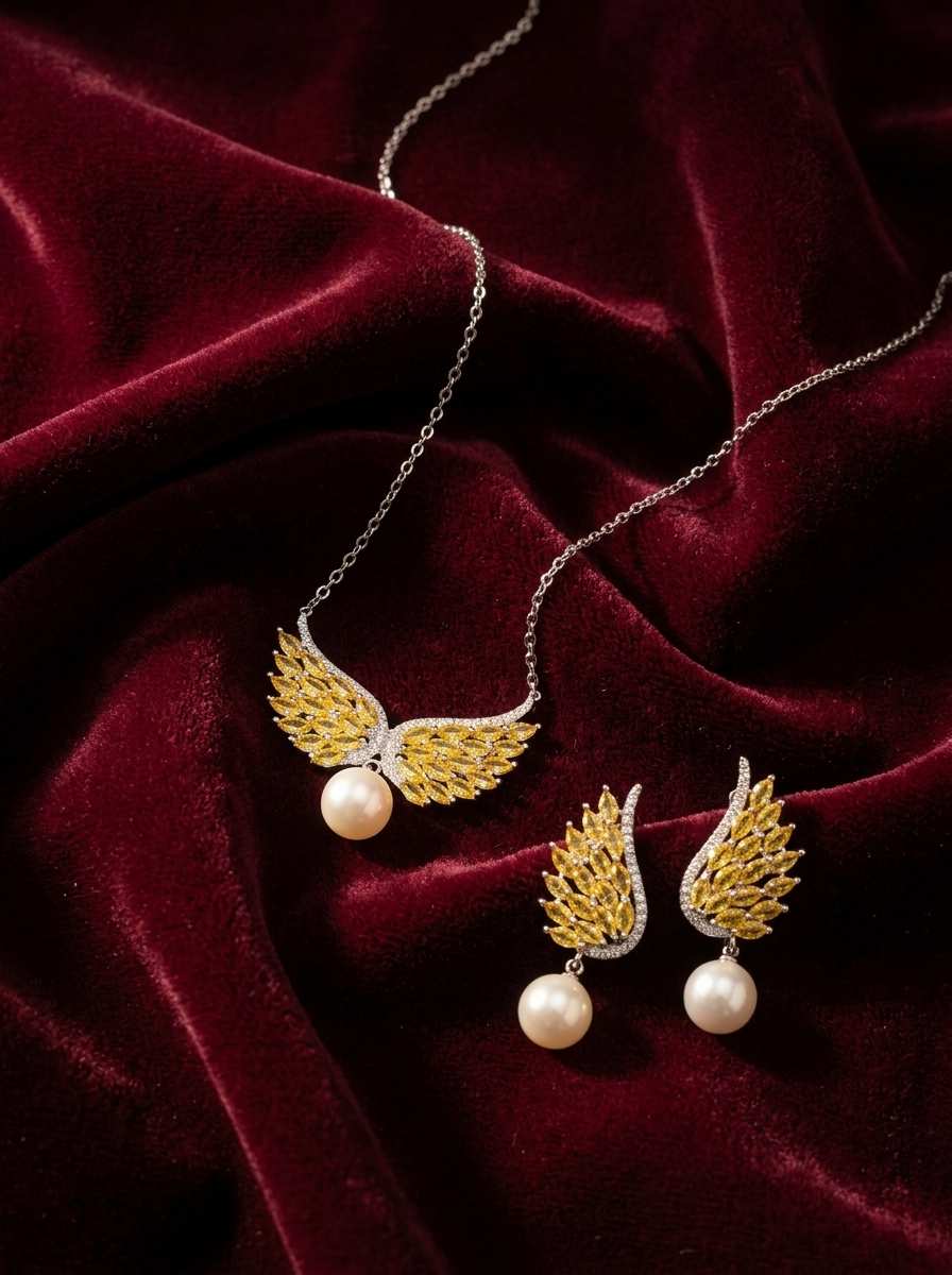 Angel Wing Set lifestyle flatlay on burgundy velvet — pendant and matching earrings together in warm cinematic side light